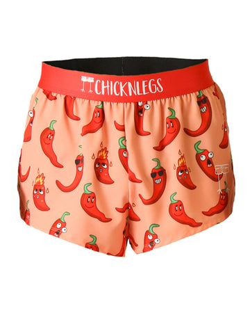 These chicknlegs shorts are the men's 2 in split running shorts in the chili pepper design, as a ghost image. These chili peppers are on an orange background with red peppers that have sunglasses and flames on it.