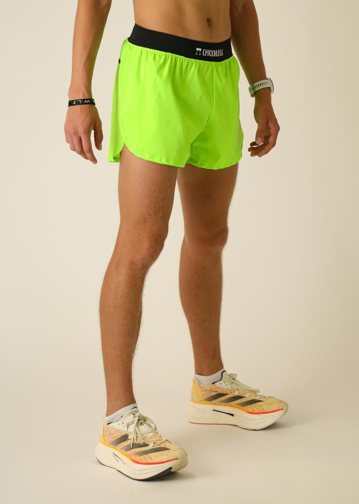 Model wearing Chicknlegs men's 4 inch split running shorts in the neon green design, facing right for right side view.