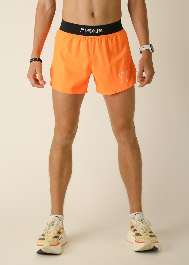 Model wearing Chicknlegs men's 4 inch split running shorts in the neon orange design, facing front.