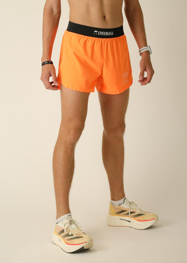 Model wearing Chicknlegs men's 4 inch split running shorts in the neon orange design, facing right for right side view.