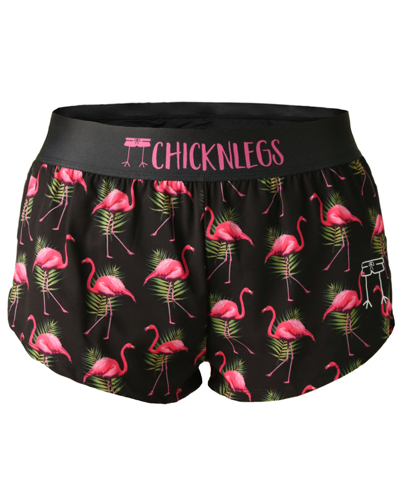 These shorts are from Chicknlegs in the women's 1.5 in split running shorts as the black flamingo design as a ghost image. The print has pink flamingos on it with green leaves on a black background.