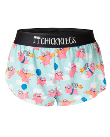 Ghost image is shown from ChicknLegs women's 1.5 in split running shorts in the flying pigs design. The print has pink pigs with goggles flying through the blue sky.