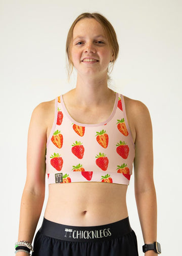 The model is a runner who is wearing Chicknlegs in the women's og sports bra in the strawberry szn design. A close up is shown.