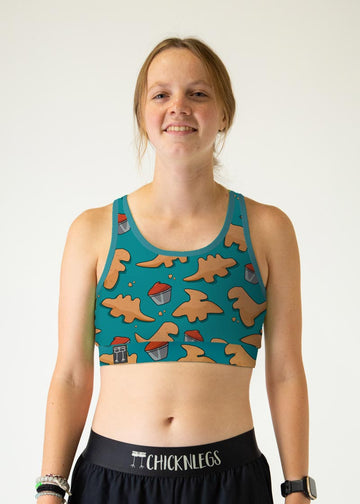 The model is a runner who is wearing Chicknlegs women's og sports bra in the dino nuggets design, facing front. A close up is shown.