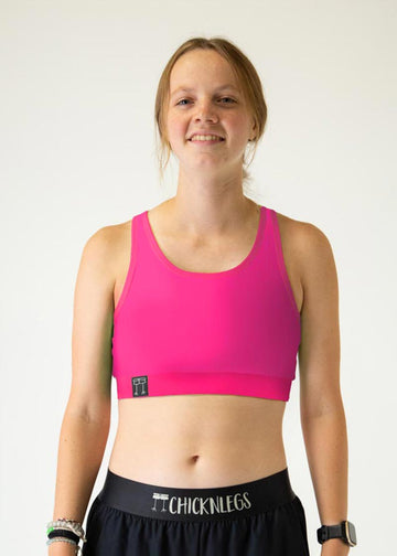 The model is a runner who is wearing Chicknlegs women's og sports bra in the neon pink design. A close up is shown.