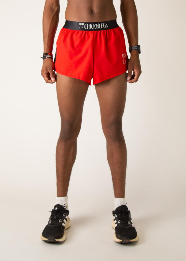 Model is wearing Chicknlegs mens 2 inch split running shorts in the red design, facing front.