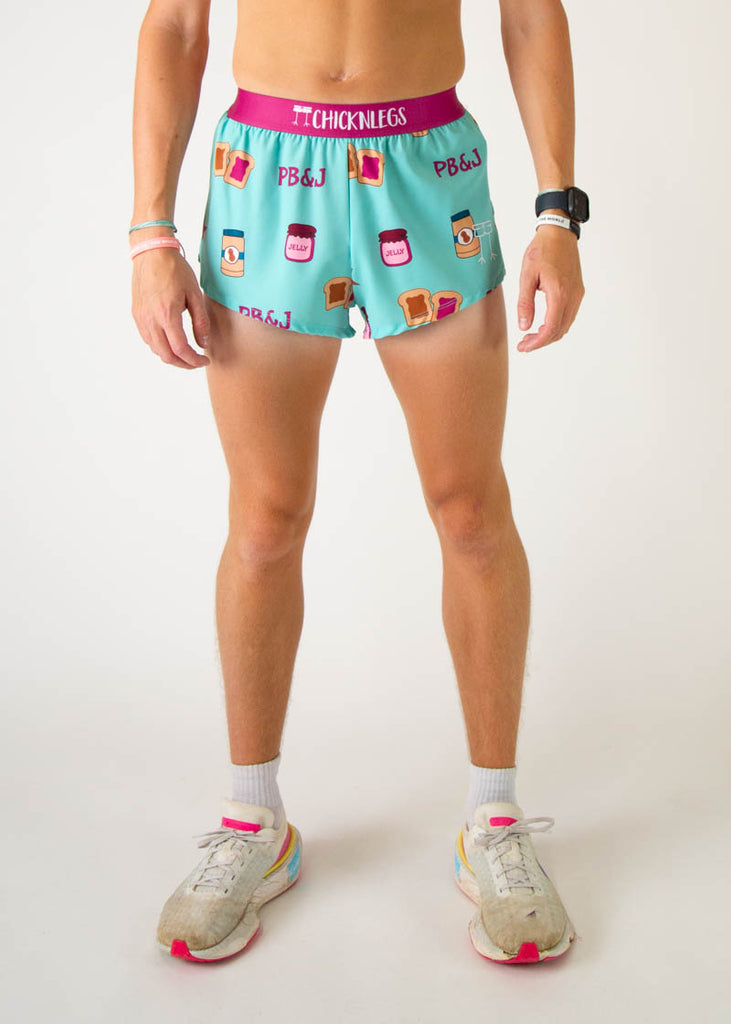 The model is a runner that is wearing athletic Chicknlegs men's 2 inch split running shorts in the PB&J design that includes PB&J sandwiches, peanut butter, jelly on a light blue background, facing front.
