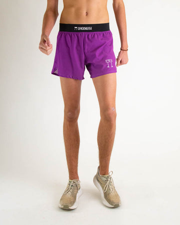 Runner is wearing ChicknLegs in the men's 4 in split running shorts with a back zipper pocket in the deep purple color facing front.