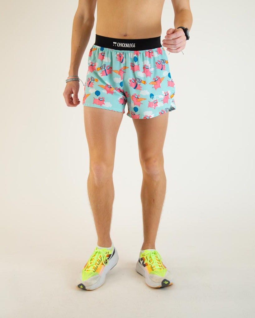 Runner is wearing ChicknLegs in the men's 4 in split running shorts in the flying pigs design, facing front. The print has pink flying pig on it with clouds, balloons, cardboard wings, and a jetpack.