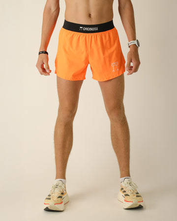 Runner is wearing ChicknLegs in the men's 4 in split running shorts with a back pocket and inner liner pocket. The print is a solid neon orange.