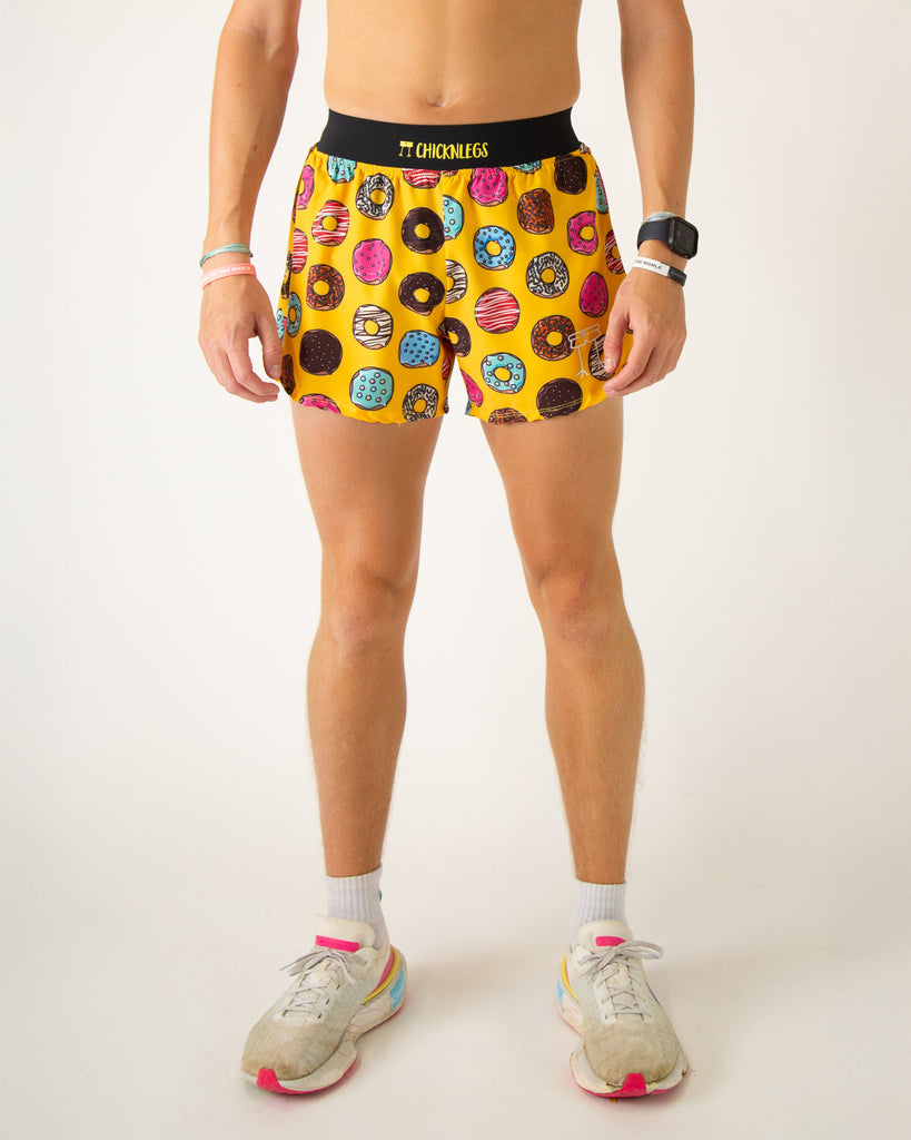 Runner is wearing ChicknLegs in the men's 4 in split running shorts with a back pocket and inner liner pocket. The print has salty donuts on it in various doughnut forms and flavors on a yellow background.