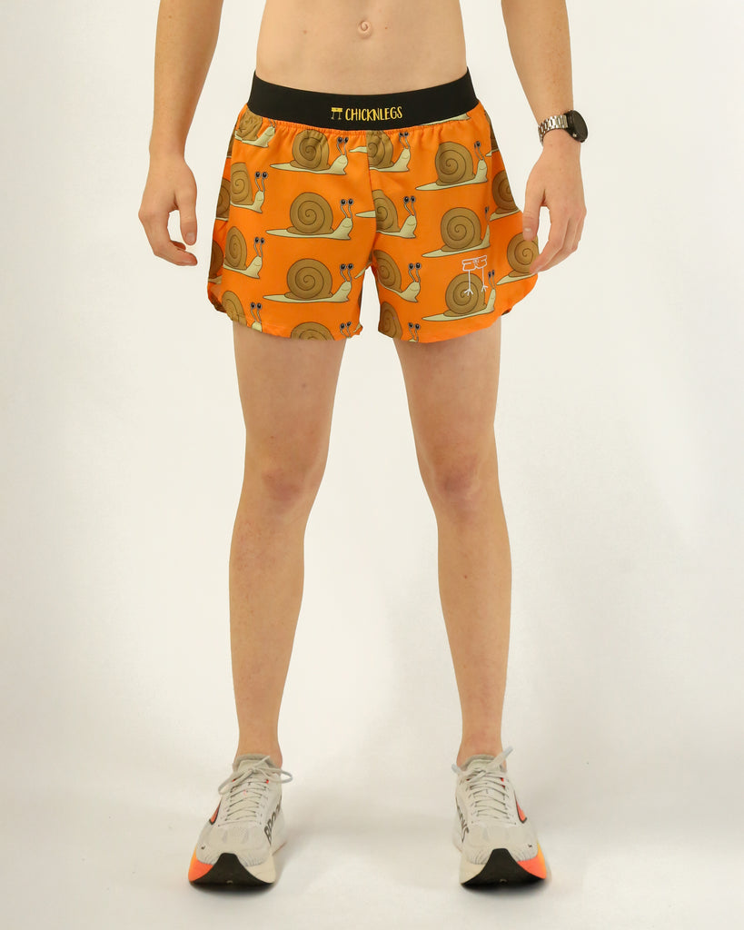 Runner is wearing ChicknLegs in a men's 4 in split running shorts with a back pocket and inner liner pocket. The print has snails on it with an orange background.