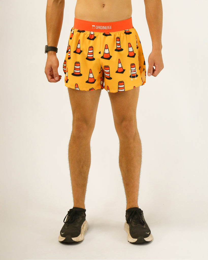 Runner is wearing ChicknLegs in the men's 4 in split running shorts with a back pocket and inner liner pocket. The print has traffic cones all over it with a light orange yellow background.