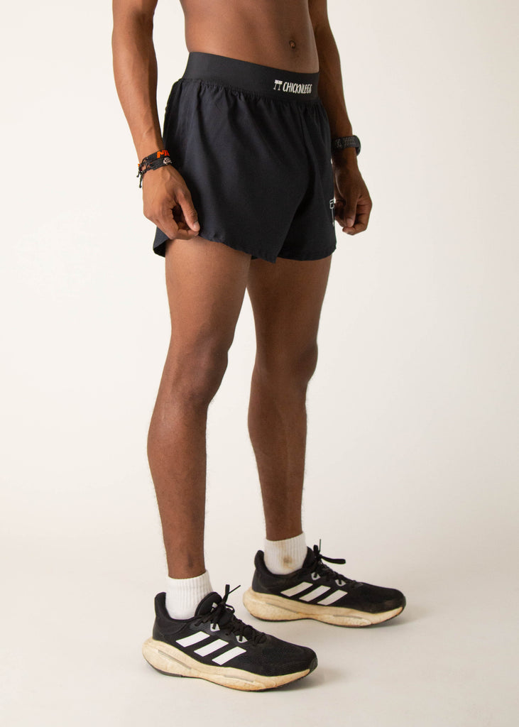 Model wearing Chicknlegs in mens 4 inch split running shorts in the black design, facing right.
