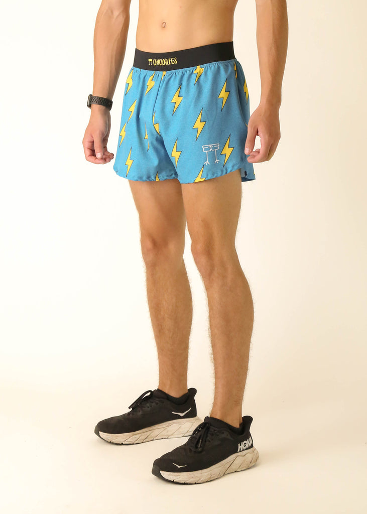 Model wearing Chicknlegs men's 4 inch split running shorts in the blue bolts design facing left side.
