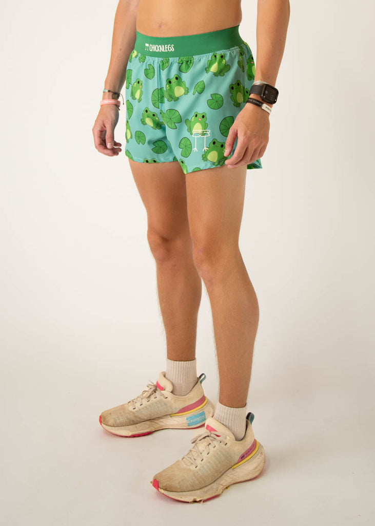 Model is a runner wearing Chicknleg's men's 4 inch split running shorts in the fartlek frog design, facing left.
