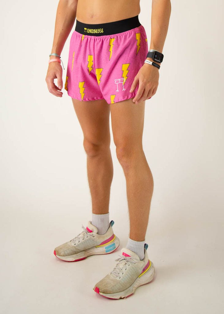 The model is a runner wearing Chicknlegs men's 4 inch split running shorts in the hot pink bolts design, facing left.
