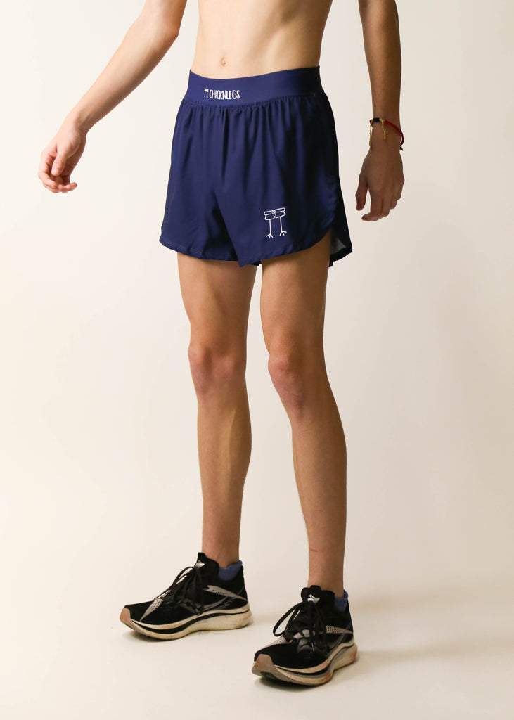 Model is a runner wearing Chicknlegs men's 4 inch split running shorts in the navy blue design facing left.