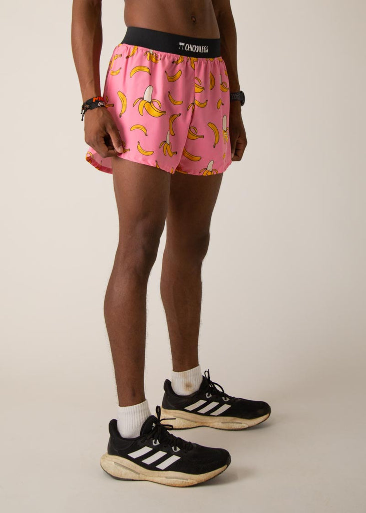 Model wearing Chicknleg's mens 4 inch split running shorts in the pink banana design, facing right.