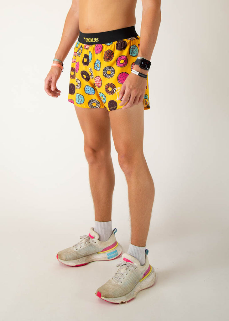 The model is a runner wearing Chicknlegs in the men's 4 inch split running shorts in the salty donuts design, facing left.
