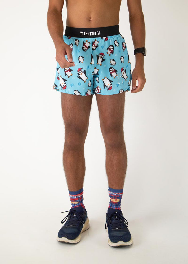 The model is a runner who is wearing Chicknlegs men's 4 inch split running short in the Slippery Bois, Penguins design, facing front.