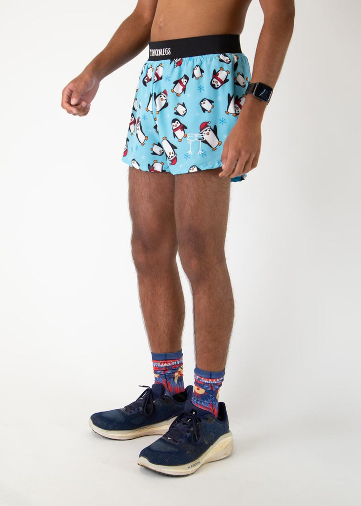 The model is a runner who is wearing Chicknlegs men's 4 inch split running short in the Slippery Bois, Penguins design, facing left.