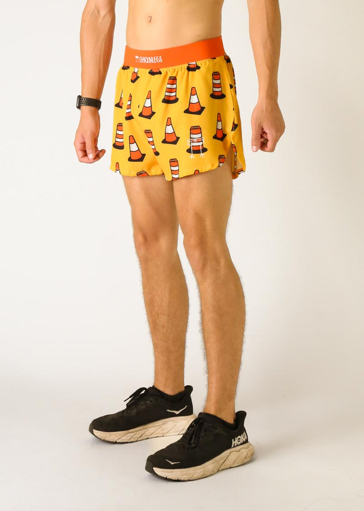 Model is a runner wearing Chicknlegs men's 4 inch split running shorts in the traffic cones design, facing left.