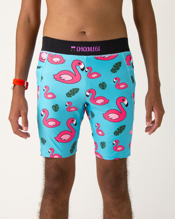 Runner is wearing ChicknLegs in the men's 8 in half tights with pockets in the blue flamingo design that has pink flamingos, green leaves and a solid blue background.