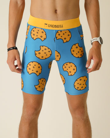 Runner is wearing ChicknLegs in the men's 8 in half tights with pockets in the cookies design. The print has fun chocolate chip cookies on it with a solid blue background.