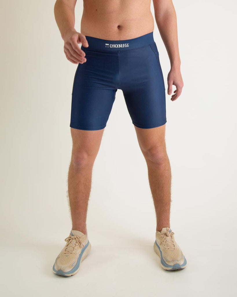 Runner is wearing ChicknLegs in the men's 8 in half tights with pockets in the navy design. The print is a solid navy blue color as a close up image. Great to protect from chaffing and long runs, a front view is shown.