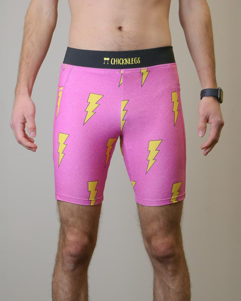 Runner is wearing ChicknLegs in the men's 8 in half tights with pockets in the pink bolts design. The print has yellow lightning bolts with hot pink solid background.