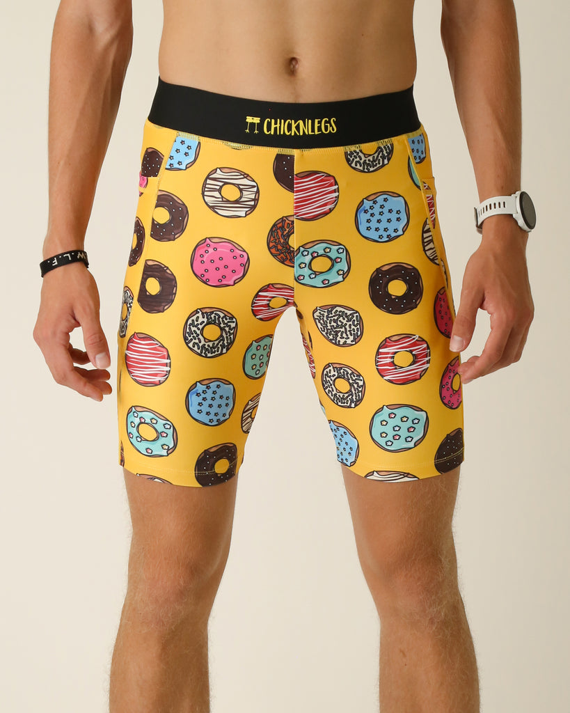 Runner is wearing ChicknLegs in the men's 8 in half tights with pockets in the salty donuts design. The print has fun doughnuts all over it in many flavors on a yellow background.