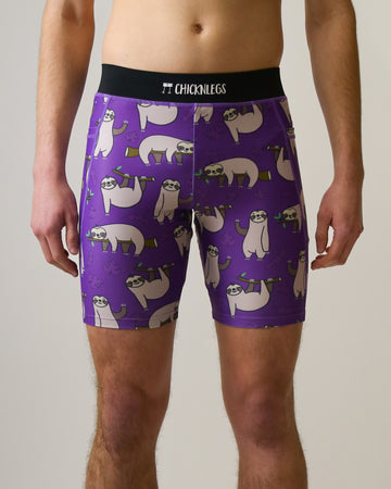 Runner is wearing ChicknLegs in the men's 8 in half tights with pockets in the sloth design. The print has fun sloths all over it with green leaves and branches on a solid purple background.