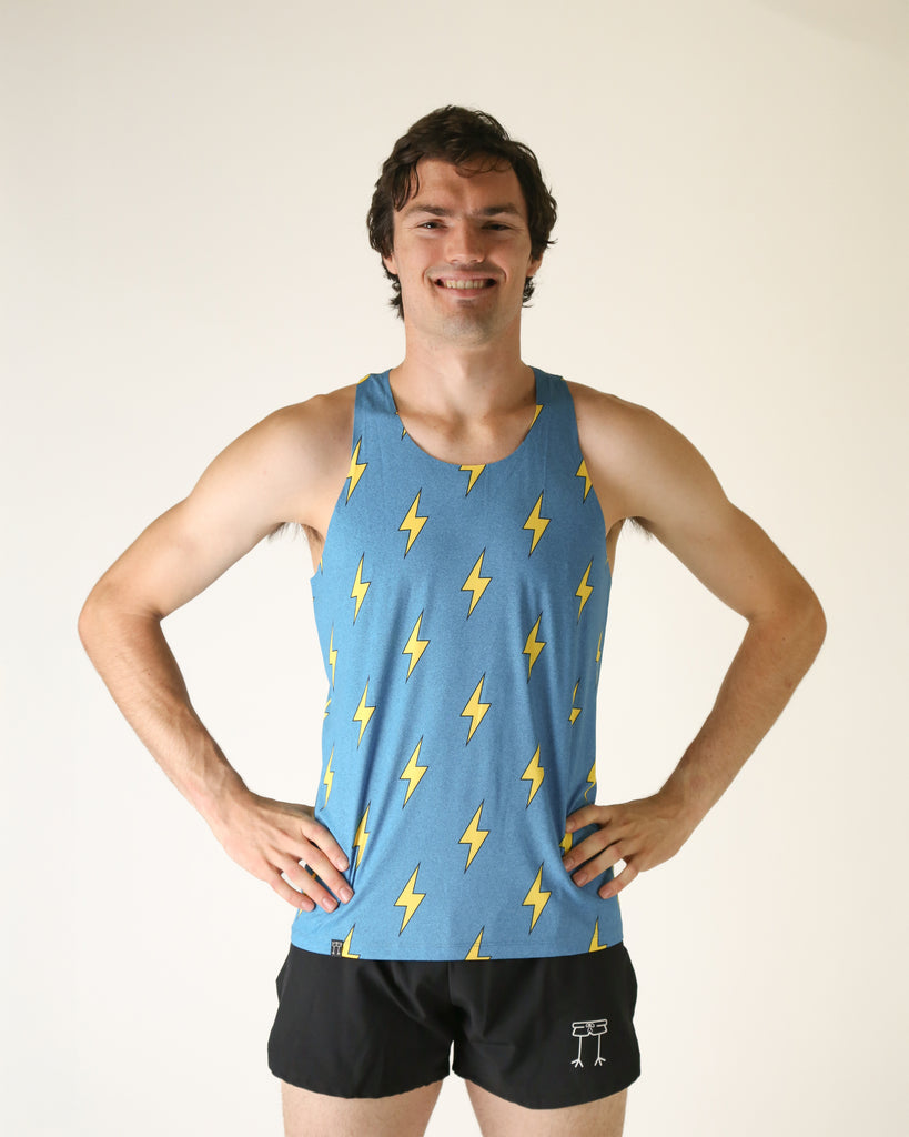 Runner is wearing ChicknLegs in the men's performance singlet that is lightweight and has the blue bolts design on it. The print has yellow lightning bolts on it with a blue background.