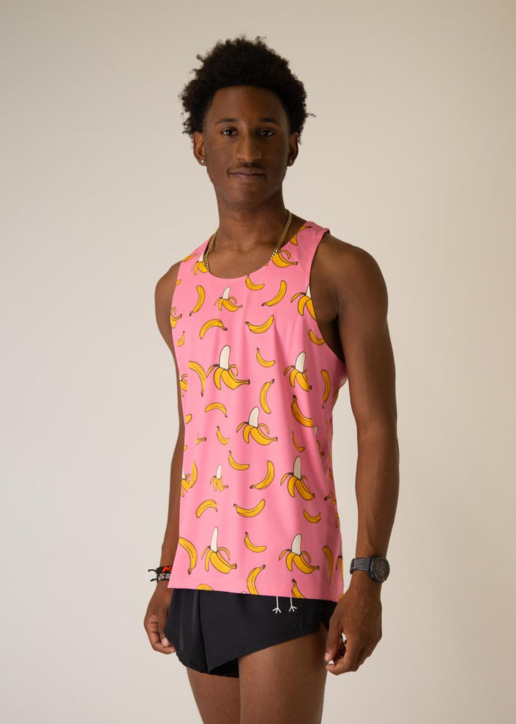 Model is wearing Chicknlegs men's runner singlet in the pink bananas design, facing left.