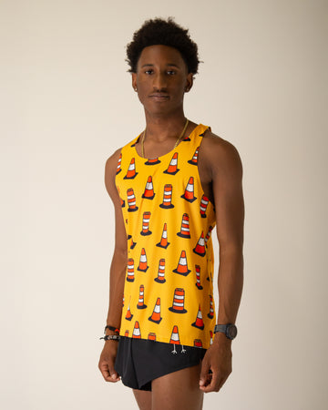 Runner is wearing ChicknLegs in the men's performance singlet. The material is lightweight and the print has traffic cones on it with a yellow orange background.