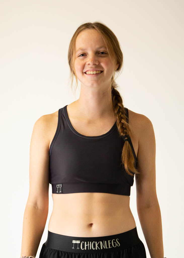 The model is a runner wearing Chicknlegs women's OG sports bra in the black design, facing front. A close up is shown.