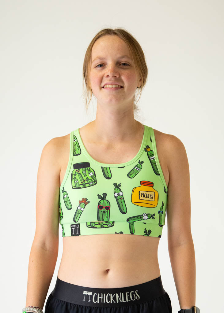 The model is a runner who is wearing Chicknlegs women's OG sports bra in the pickles design, facing front. A close up is shown.