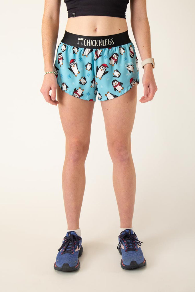 The model is a runner who is wearing Chicknlegs women's 1.5" split running shorts in the slippery bois penguins design, facing front.