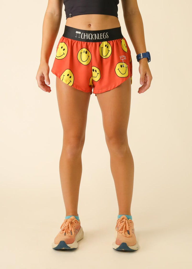 Model is wearing Chicknlegs women's 1.5 inch split running shorts in the smiley design facing front.