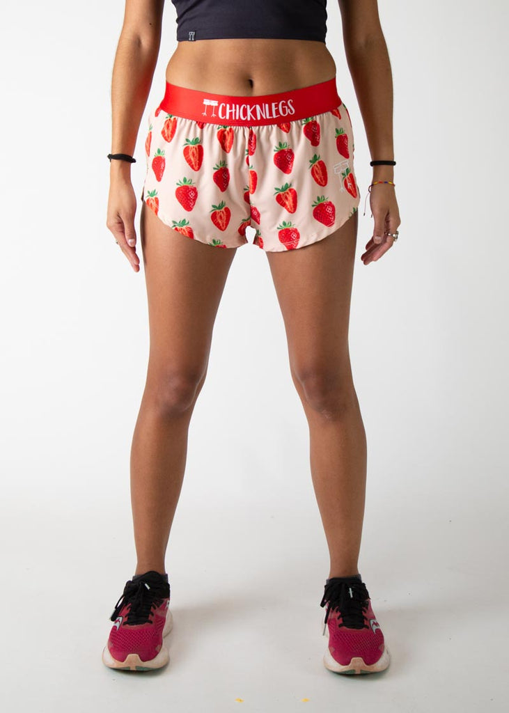 Model is a runner wearing Chicknlegs womens 1.5 inch split running shorts in the strawberry szn design, facing front.