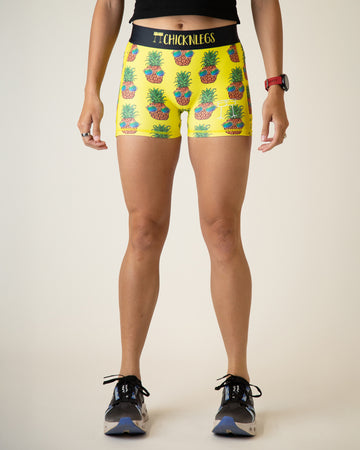 Runner is wearing ChicknLegs women's 3 in compression spandex in the pineapple express design. The print has pineapples with sunglasses on it with a yellow background.