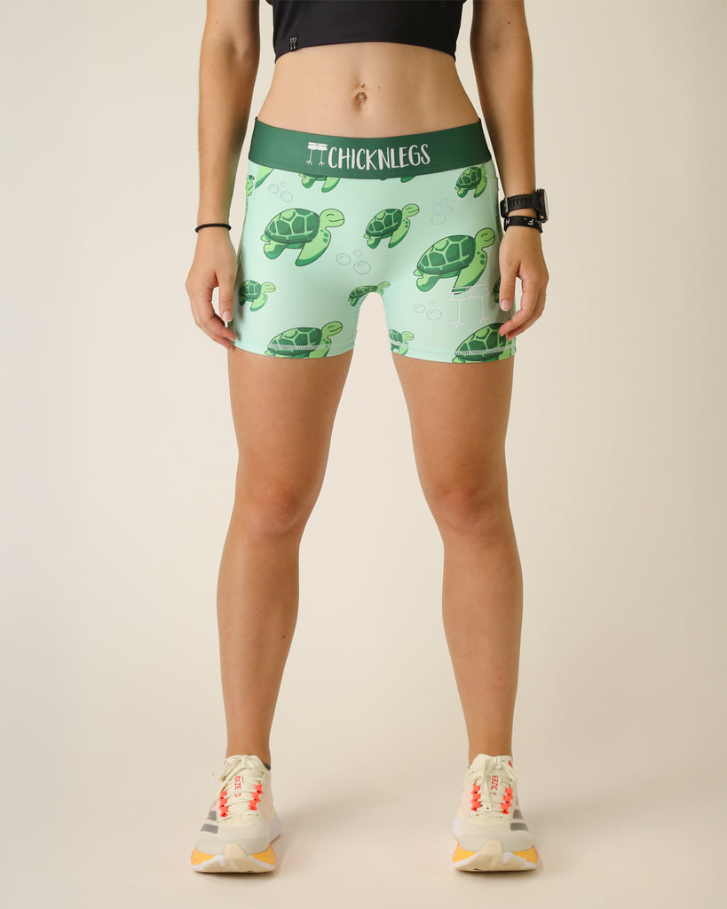 Runner is wearing ChicknLegs in the women's 3 in compression spandex shorts in the sea turtle design. The print has green turtles on it, bubbles and a light green background.