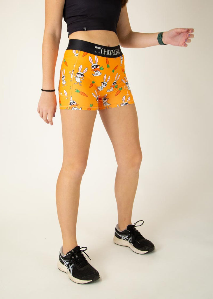 Runner is wearing ChicknLegs in the women's compression spandex in the bad bunny design, facing right showing the side pockets. The print has white rabbit on it with sunglasses and carrots, flexing their muscles and gold chains.