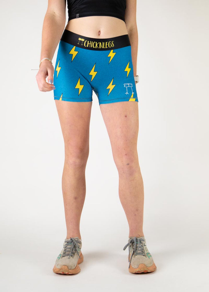 The model is a runner who is wearing Chicknlegs in the women's 3" compression shorts in the blue bolts design, facing front.