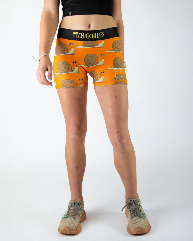 Runner is wearing ChicknLegs in the women's 3 in compression spandex in the snails design. The print has snails with an orange background.