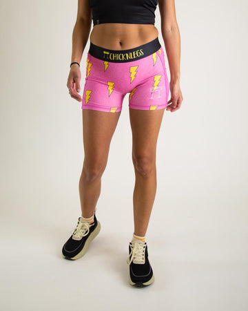 Runner is wearing ChicknLegs in the women's 3 in compression spandex shorts in the hot pink bolts design. The print has yellow lightning bolts on it with a hot neon pink background.