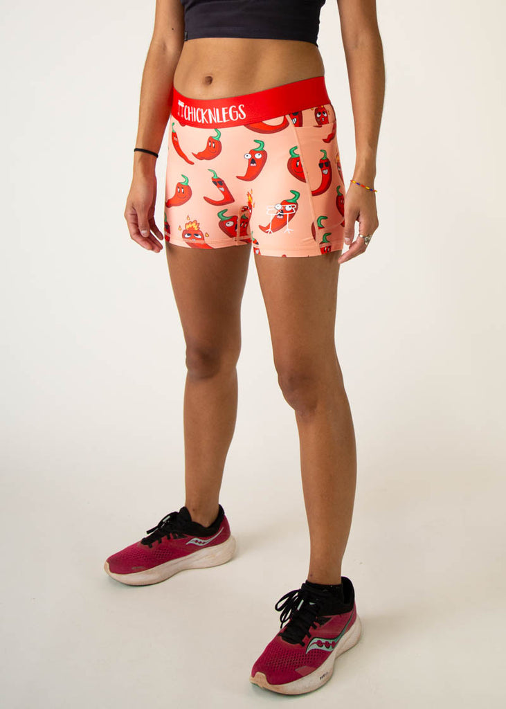 Model is a runner wearing Chicknlegs women's 3 inch compression shorts in the chili pepper design, facing left.