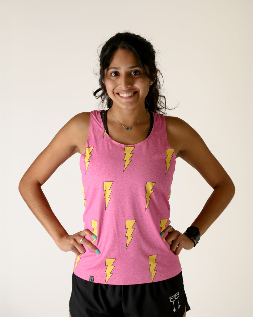 Runner is wearing ChicknLegs in the women's performance singlet in the hot pink bolts design. The print has yellow lightning bolts on it with a bright hot neon pink background.