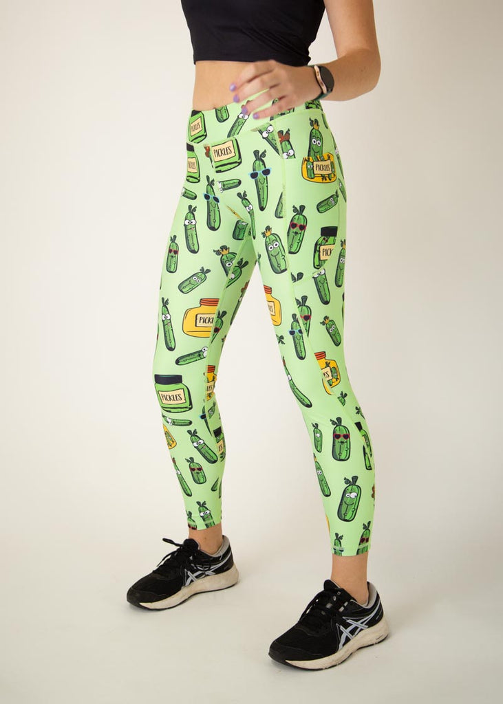 The model is a runner who is wearing Chicknlegs Women's Leggings in the Pickles design. These leggings include side pockets and an adjustable drawstring at the front. The model is facing slightly left.